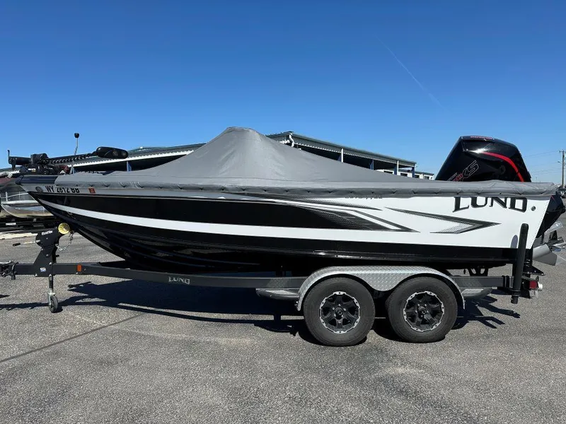 Slide: The Image of 2020 Lund 1875 Tyee boat on trailer, covered, parked outdoors under clear blue sky. - 2