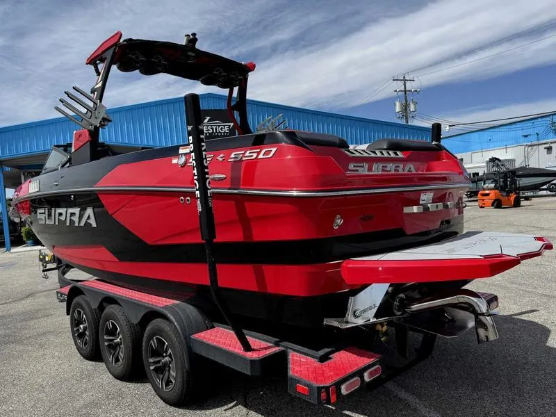Slide: The Image of 2019 Supra SE550 boat in red and black on a trailer, parked outdoors. - 5