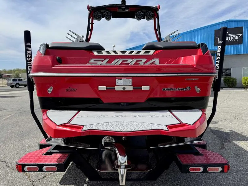 Slide: The Image of Red 2019 Supra SE550 boat rear view, parked outdoors near a blue building. - 7
