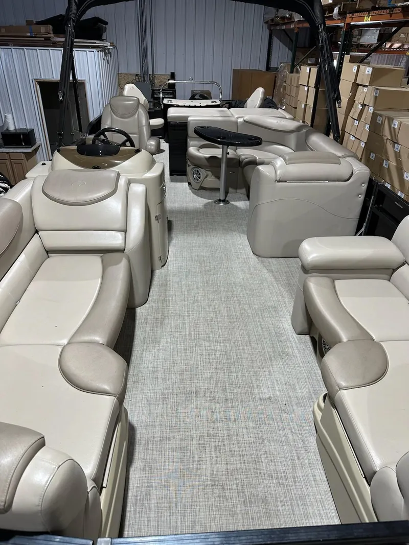 Slide: The Image of 2017 Avalon 2585 RF pontoon boat interior with beige seating and central table. - 2