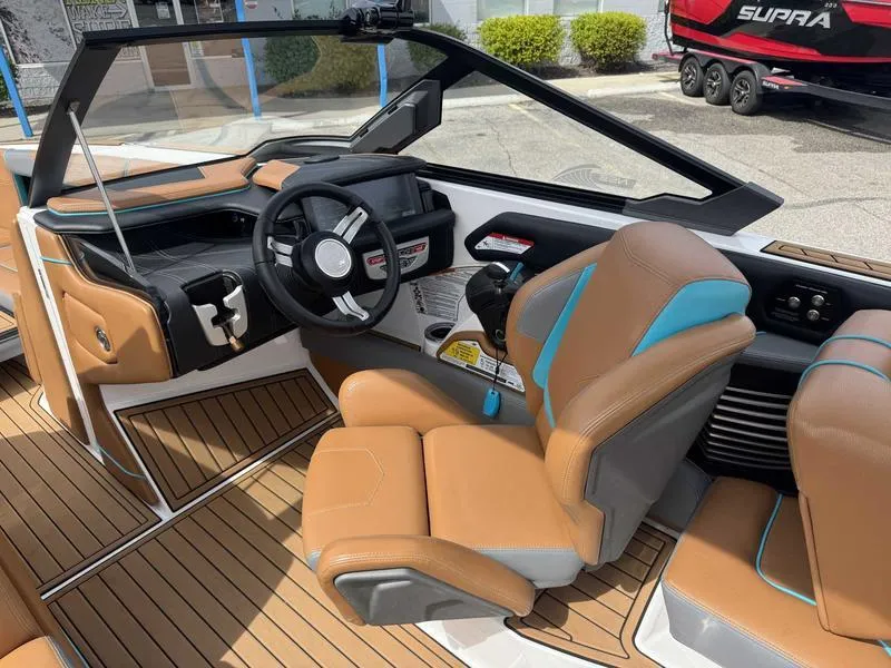 Slide: The Image of 2019 Nautique G25 boat interior with tan and blue seating, modern dashboard, and steering wheel. - 10