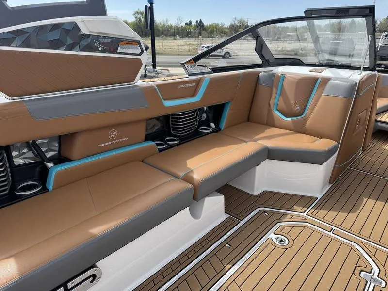 Slide: The Image of 2019 Nautique G25 boat interior with brown and gray seating, featuring blue accents and teak flooring. - 11