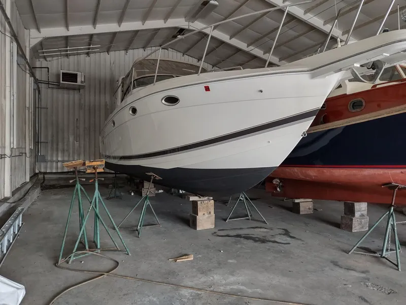 Slide: The Image of 2000 Formula 31PC boat in storage, supported by stands in a warehouse. - 0