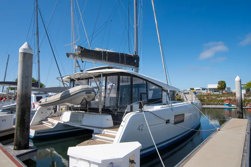Slide: The Image of 2017 Lagoon 42 catamaran docked at marina under clear blue sky. - 12