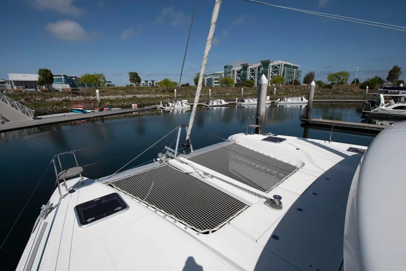 Slide: The Image of 2017 Lagoon 42 catamaran docked in a marina with modern buildings in the background. - 17