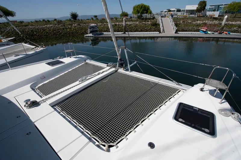 Slide: The Image of 2017 Lagoon 42 catamaran docked, featuring netted deck and calm marina surroundings. - 18