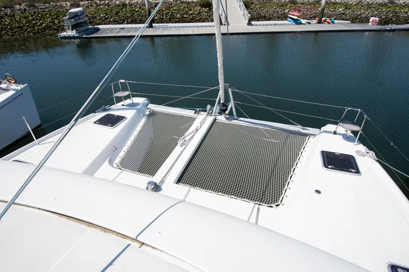 Slide: The Image of 2017 Lagoon 42 catamaran with netted deck, docked in a marina. - 22