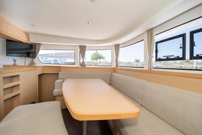 Slide: The Image of Interior of 2017 Lagoon 42 catamaran with dining area, beige seating, and large windows. - 43