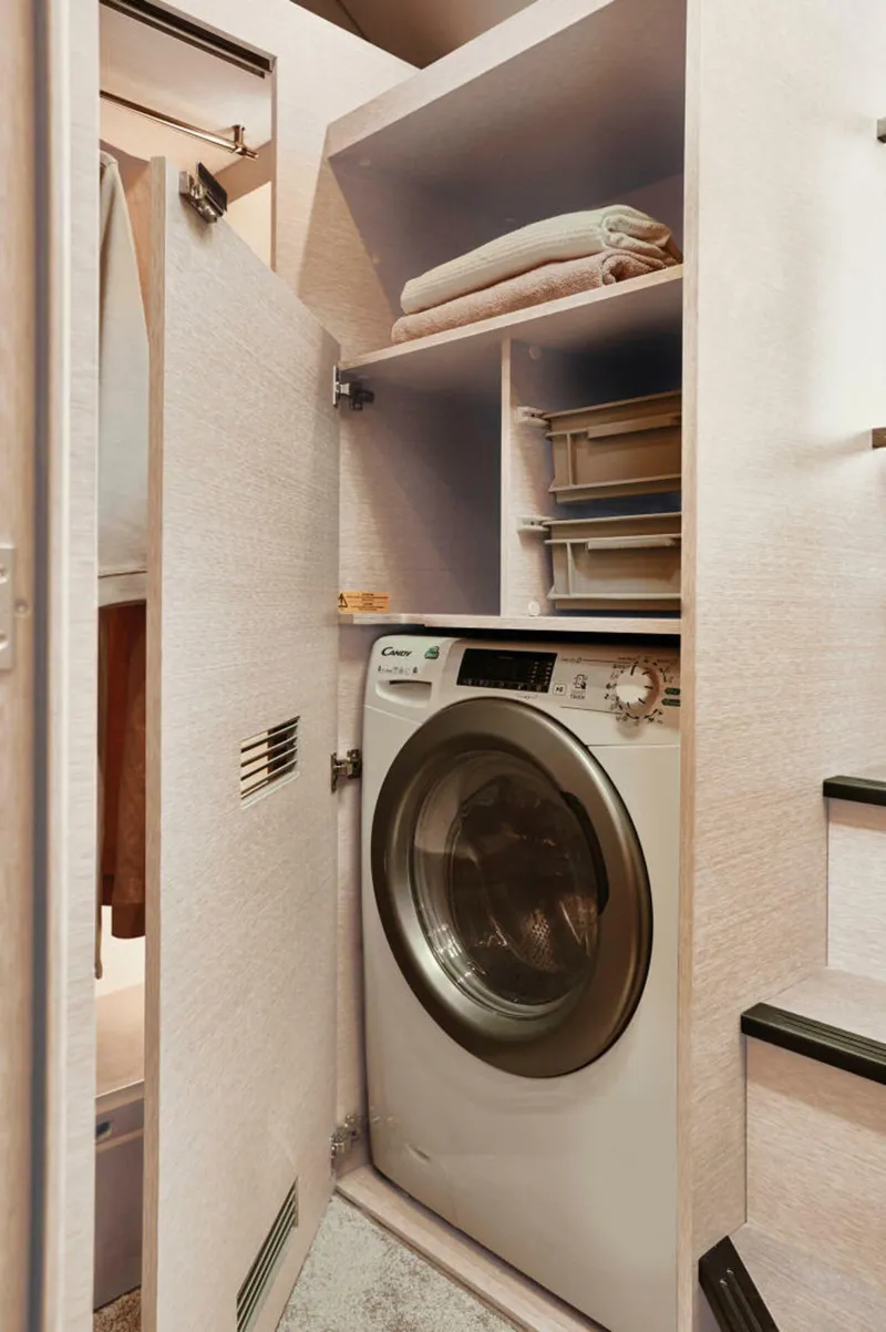 Slide: The Image of Compact laundry area in a 2025 Prestige 420S yacht with washer and storage shelves. - 12