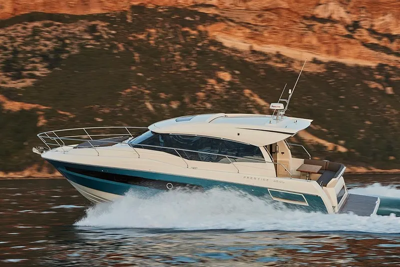 Slide: The Image of 2023 Prestige 460S yacht cruising on water with scenic rocky backdrop. - 4
