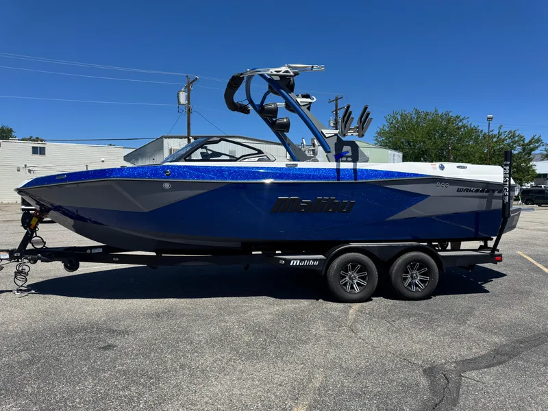 The Image of 2024 Malibu Wakesetter 23 LSV boat on trailer, blue and gray design, parked outdoors. - 1