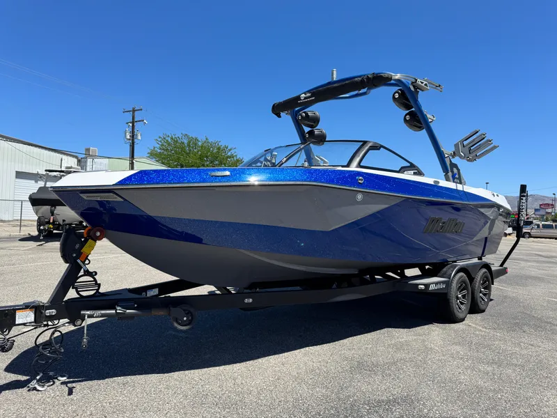 Slide: The Image of 2024 Malibu Wakesetter 23 LSV boat on trailer, blue and white design, sunny day. - 2