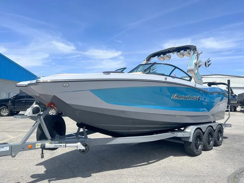 Slide: The Image of 2023 MasterCraft X24 boat on a trailer, featuring a sleek blue and white design. - 34