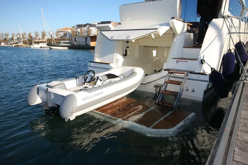 Slide: The Image of 2024 Prestige 520S yacht with tender boat on water, docked at marina. - 2