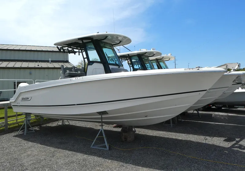 Slide: The Image of 2025 Boston Whaler 250 Outrage boat displayed on stands outdoors. - 0