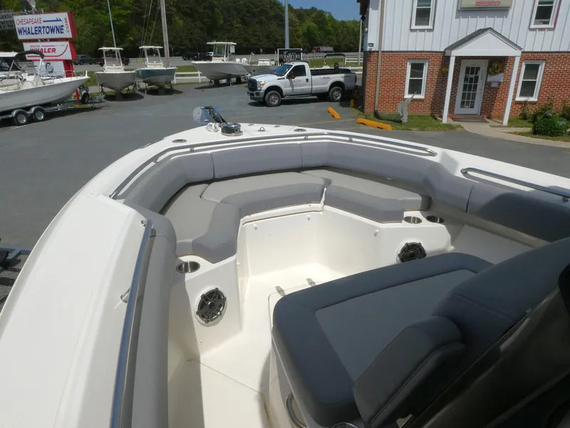Slide: The Image of 2025 Boston Whaler 250 Outrage boat with spacious seating, parked near a dealership. - 13