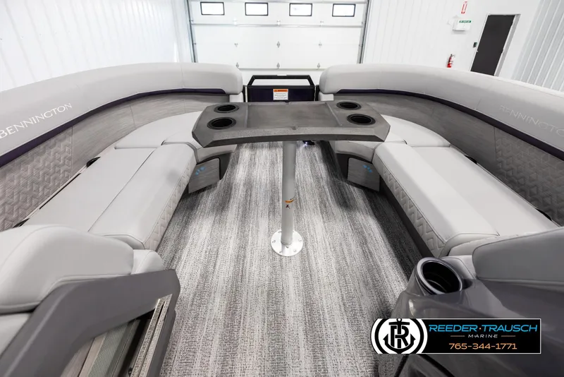 Slide: The Image of 2025 Bennington 22 MFBSE boat interior with gray seating and table, showcased in a showroom. - 20