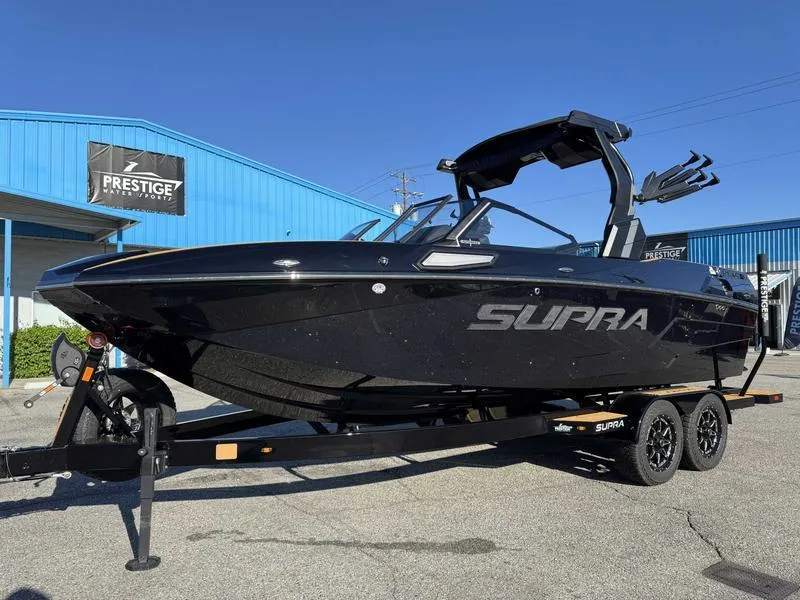 Slide: The Image of 2025 Supra SL boat in black on a trailer, parked outside a blue building. - 3