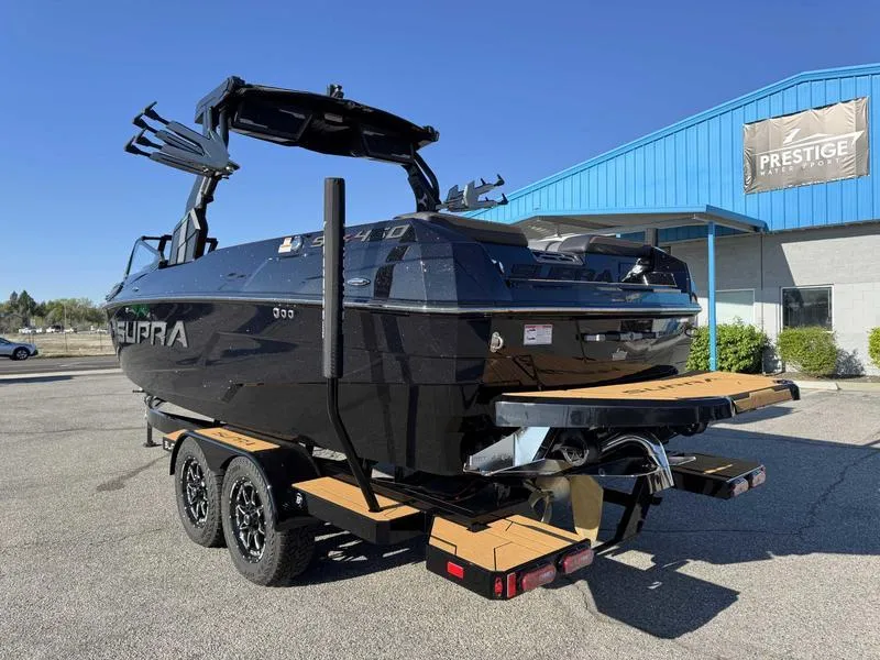 Slide: The Image of 2025 Supra SL boat on trailer, parked outside a blue building under clear skies. - 6