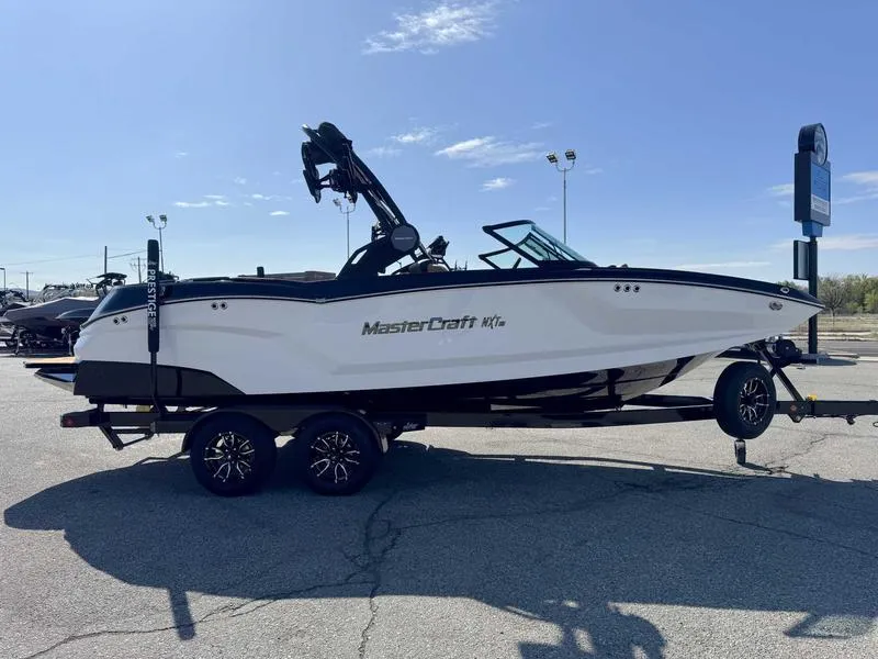 Slide: The Image of 2025 MasterCraft NXT22 boat on trailer, parked outdoors under clear sky. - 4