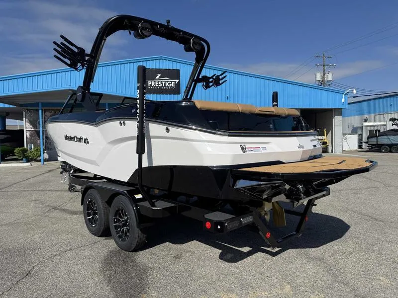 Slide: The Image of 2025 MasterCraft NXT22 boat on trailer, parked outside a blue building. - 5
