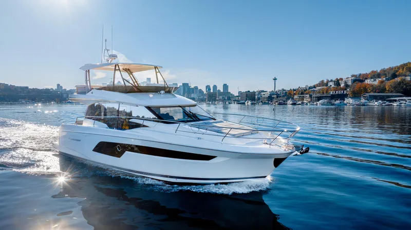 The Image of 2023 Prestige 520 yacht cruising on a sunny day with city skyline in the background. - 0