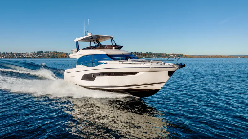 Slide: The Image of 2023 Prestige 520 yacht cruising on open water under clear blue sky. - 1