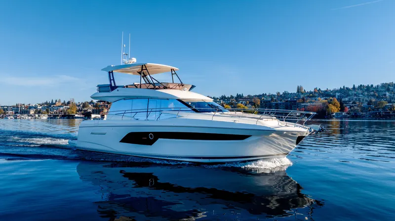 Slide: The Image of Luxury 2023 Prestige 520 yacht cruising on a serene lake under clear blue skies. - 3