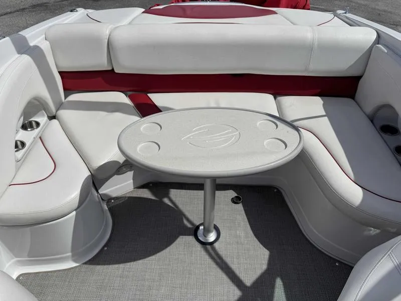 Slide: The Image of 2008 Crownline 230LS boat interior with white and red seating, round table, and cup holders. - 2