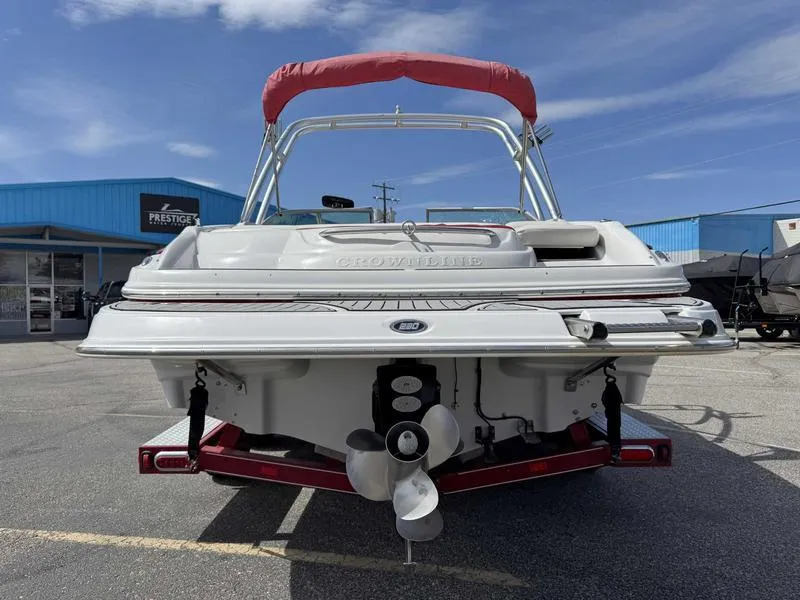 Slide: The Image of 2008 Crownline 230LS boat, rear view, parked on a trailer under a clear blue sky. - 6