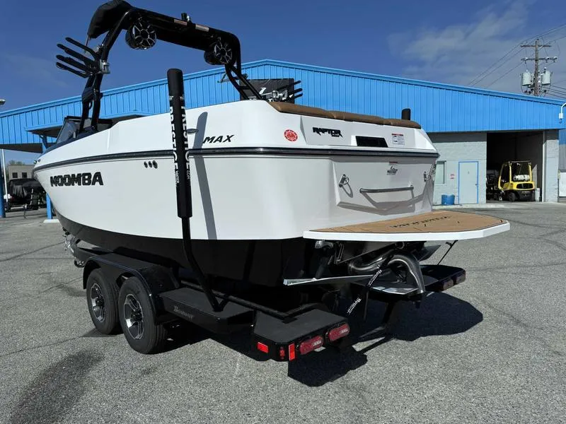 Slide: The Image of 2024 Moomba Max boat on trailer, parked outside a blue building. - 5