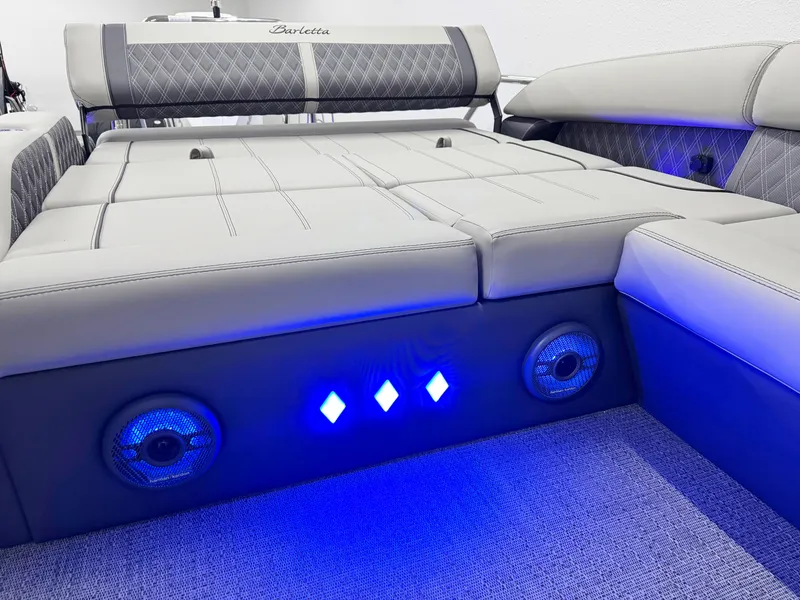 Slide: The Image of 2025 Barletta Reserve Leggera R26UCA boat interior with blue LED lights and cushioned seating. - 18