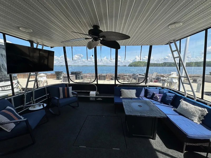 Slide: The Image of Houseboat interior with blue seating, ceiling fan, and lake view. Sumerset 16x73, 1994 model. - 1