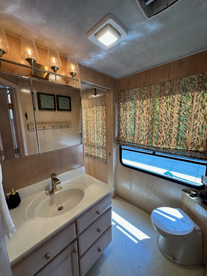 Slide: The Image of 1994 Sumerset 16x73 houseboat bathroom with sink, mirror, and window with patterned curtains. - 11
