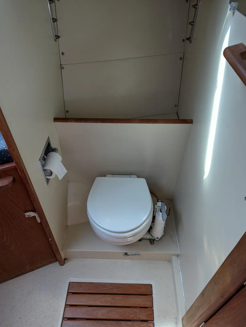 Slide: The Image of 1984 Islander 28 sailboat bathroom with toilet and wooden floor mat. - 11