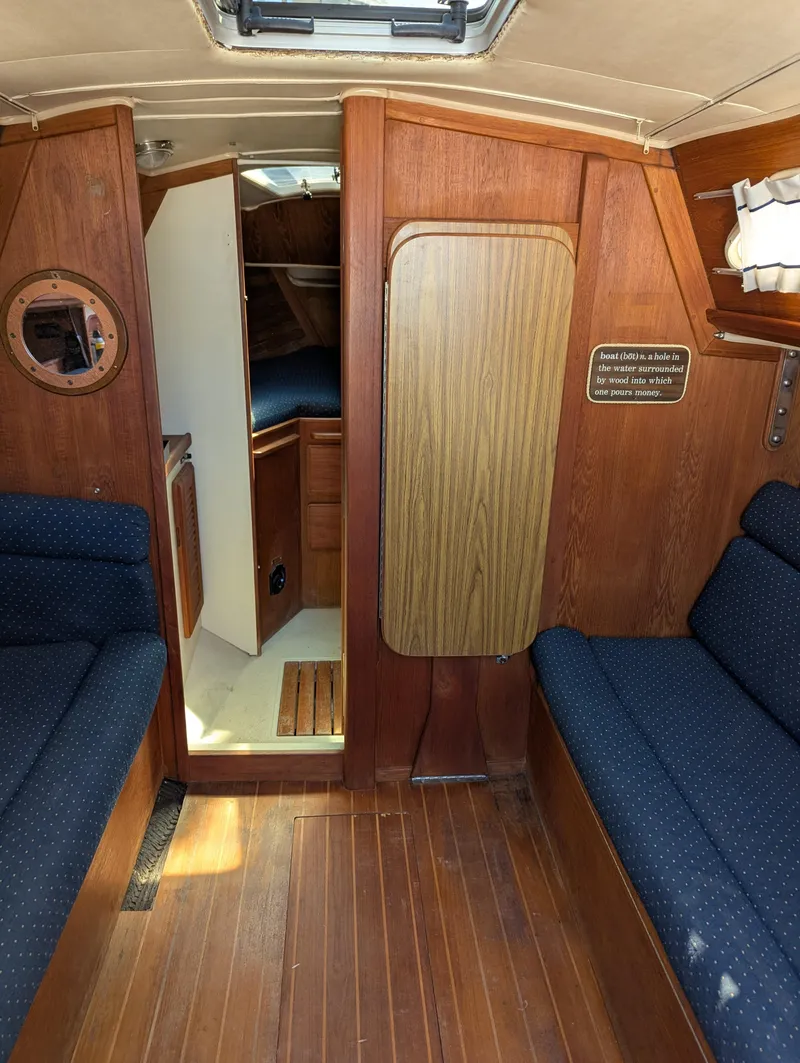 Slide: The Image of Interior of a 1984 Islander 28 sailboat with wood paneling and blue seating. - 13