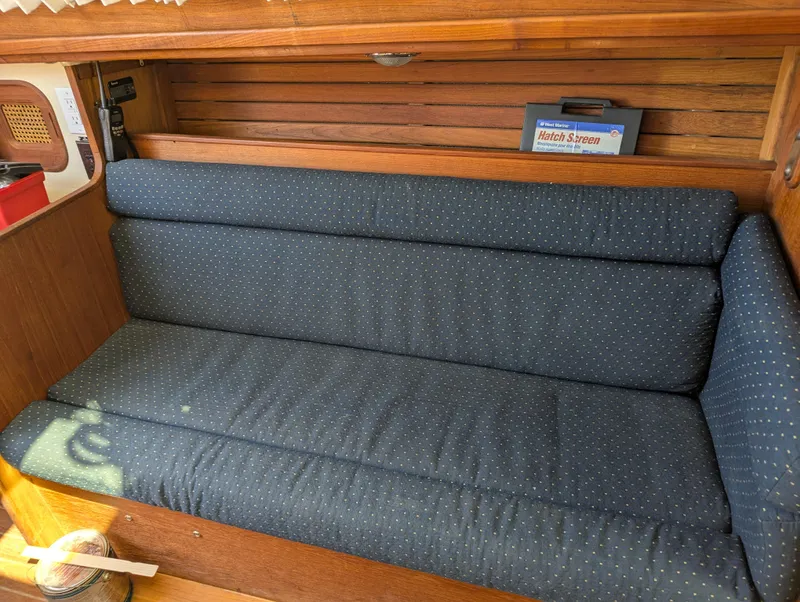 Slide: The Image of 1984 Islander 28 sailboat interior with blue cushioned seating and wooden paneling. - 14