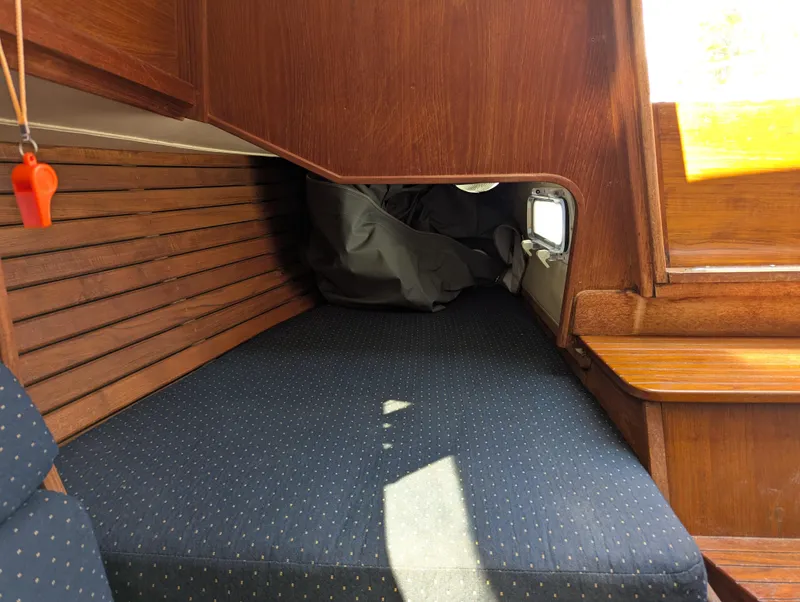 Slide: The Image of 1984 Islander 28 sailboat interior with wooden paneling and blue cushioned seating. - 16