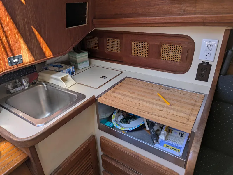 Slide: The Image of 1984 Islander 28 yacht kitchen with sink, wooden cabinetry, and countertop storage. - 18