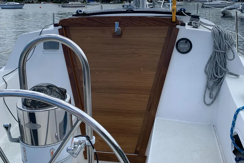 Slide: The Image of 1984 Islander 28 sailboat cockpit with wooden hatch, steering wheel, and coiled rope. - 9