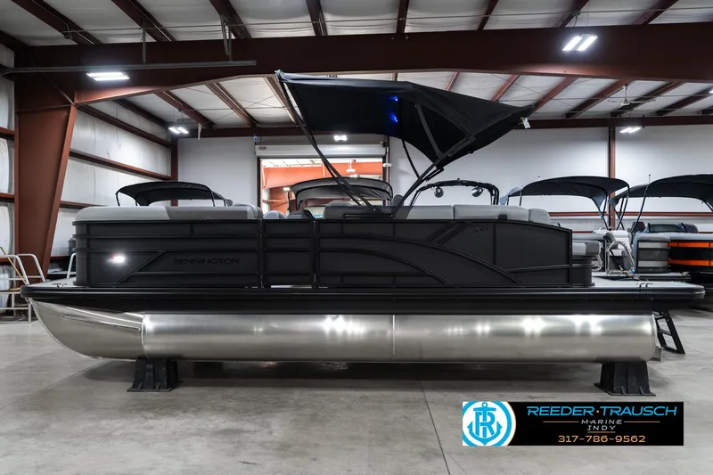Slide: The Image of 2025 Bennington 21 SLJ pontoon boat in showroom, black exterior, sleek design. - 12
