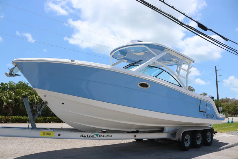 The Image of 2023 Robalo R317 boat on trailer under clear blue sky. - 0