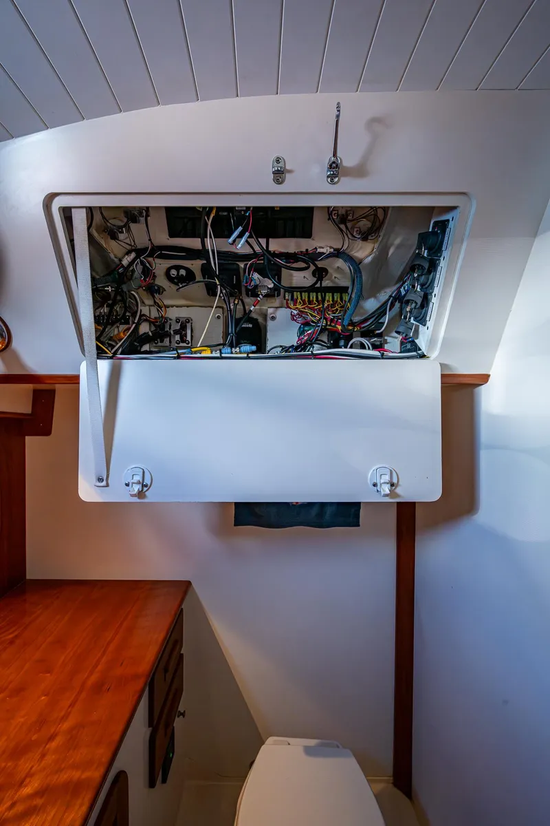 Slide: The Image of Hinckley Picnic Boat 37 MKIII 2017 interior showing open electrical panel above a toilet. - 24