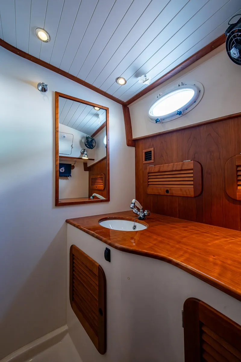 Slide: The Image of 2017 Hinckley Picnic Boat 37 MKIII bathroom with wooden cabinetry and round porthole. - 25