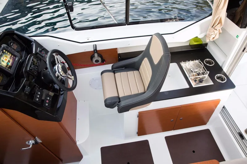 Slide: The Image of 2025 Jeanneau NC 795 boat interior with helm, seating, and control panel. - 13