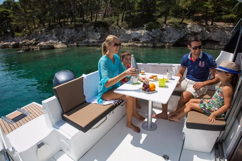 Slide: The Image of Family enjoying a meal on a 2025 Jeanneau NC 795 boat, surrounded by scenic water. - 8