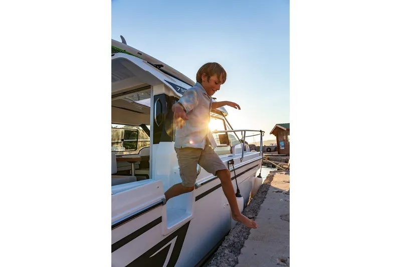 Slide: The Image of Young boy jumping off Jeanneau NC 795 Series 2 boat, 2025 model, at sunset. - 46