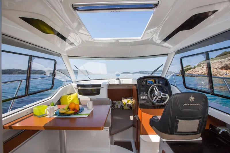 Slide: The Image of Interior of 2025 Jeanneau NC 795 boat with dining area and helm, overlooking the sea. - 17
