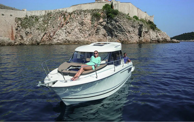 Slide: The Image of 2025 Jeanneau NC 795 boat cruising near rocky coastline. - 2