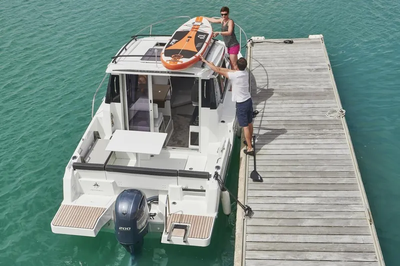 Slide: The Image of 2025 Jeanneau NC 795 Series 2 docked, with paddleboard on roof, in turquoise water. - 31